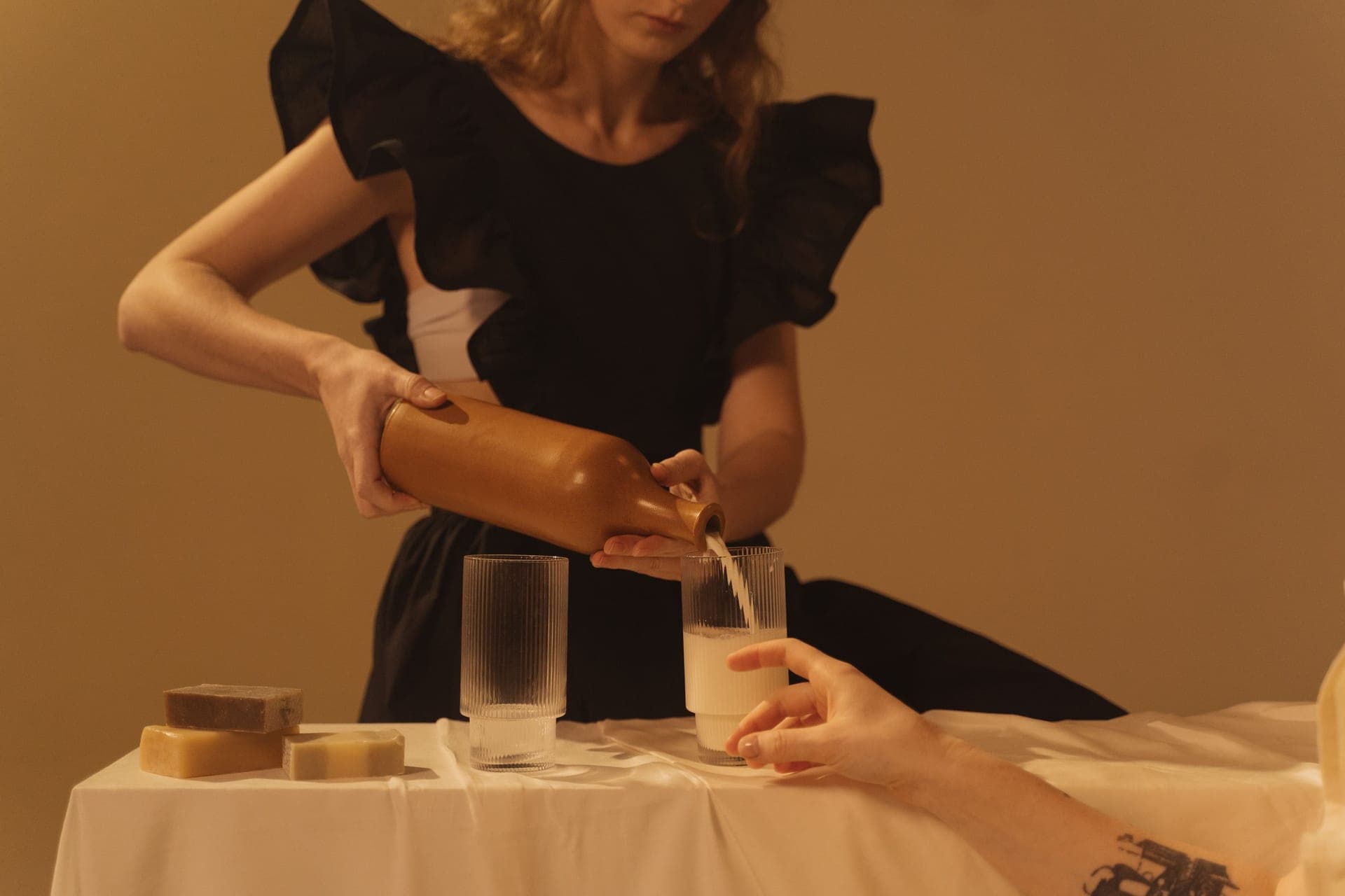 Milk being poured from a bottle into a glass on a set table (illustrative photo)