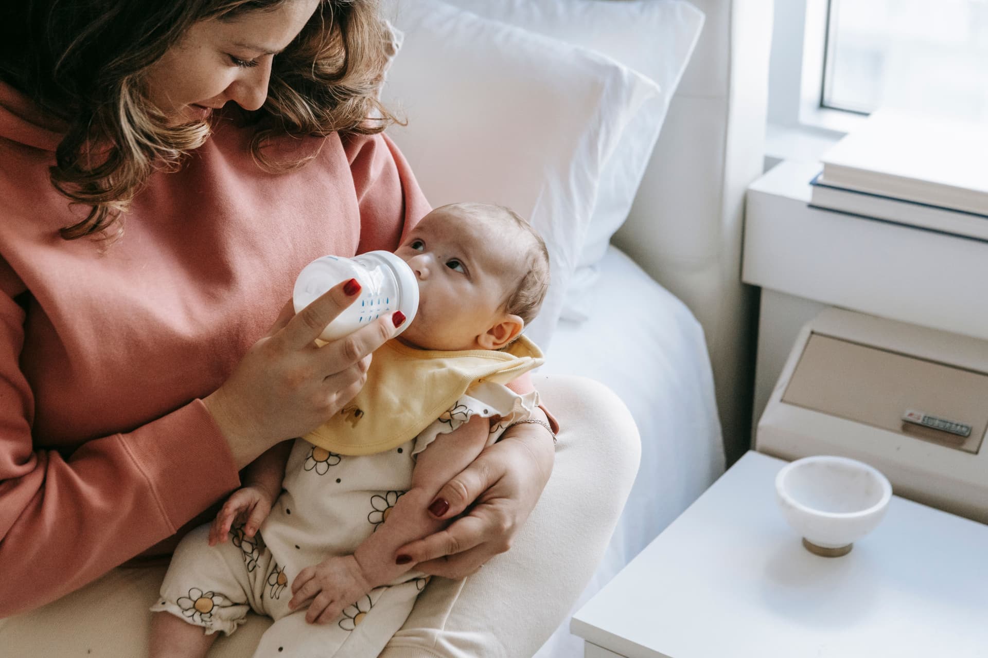 A smiling parent feeding their baby milk from a bottle (illustrative photo)