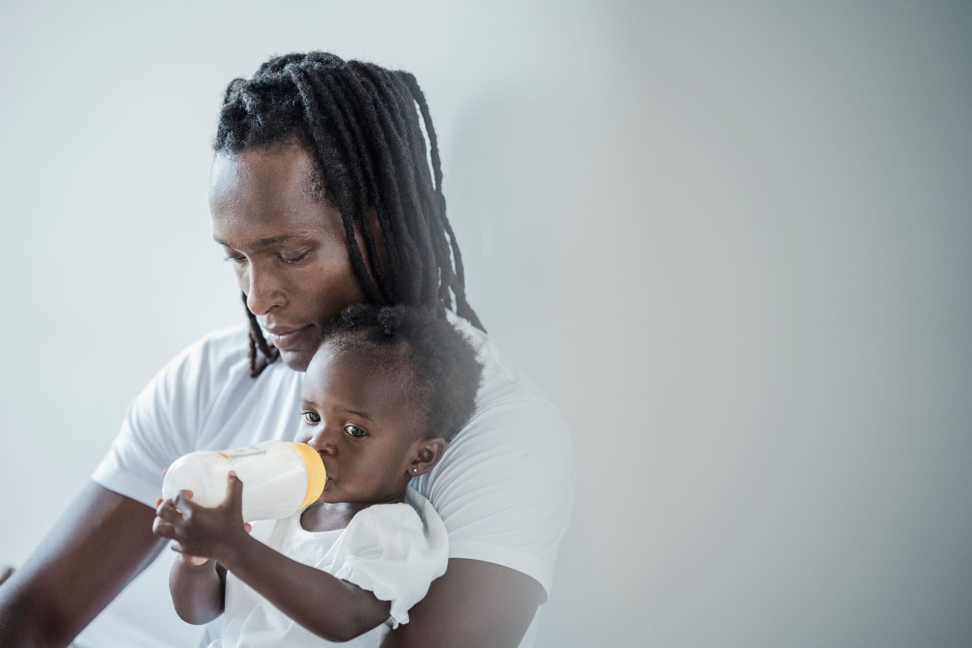 A father cradling his daughter while she drinks milk from a bottle (illustrative photo)
