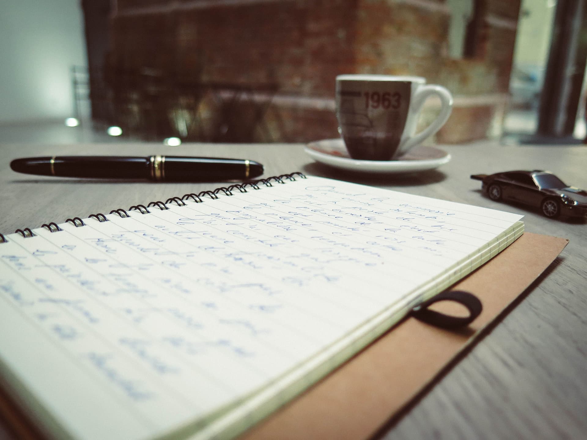 Handwritten notes, a pen and a coffee on a desk (illustrative photo)