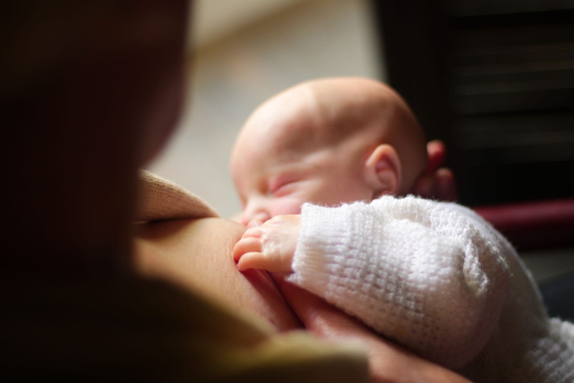 A parent holding their newborn close during a feed (illustrative photo)